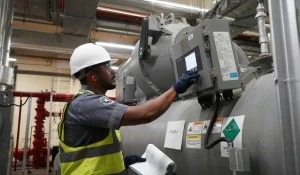 Chiller maintenance technician inspecting and operating industrial chiller equipment at a facility in Dubai.