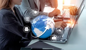 Travel company professionals using a laptop to plan trips and manage travel bookings, featuring a globe, airplane, calendar, hotel, and tourism icons representing comprehensive travel planning services.